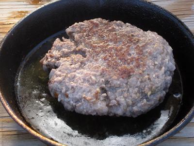 Cooked lamb burger in pan.